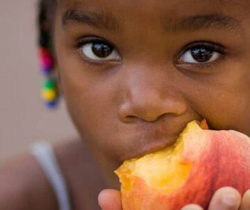 young girl eating a peach
